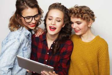 Üç hippi kız arkadaş dijital tablet kullanıyor.