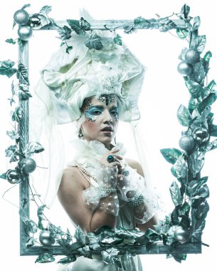 Parti, Noel ve insanlar: Noel karnavalı için kostüm giymiş güzel bir kadın Noel süslemeleri ve gümüş yapraklar çerçevesinde poz veriyor. Yaratıcı makyaj, saç stili.