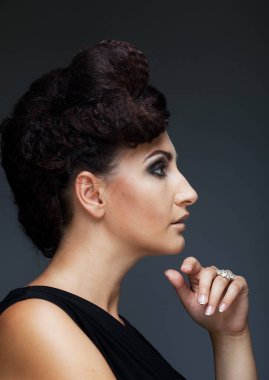 Gri arka planda poz veren zarif orta yaşlı bir kadın. Güzel saçlı ve makyajlı bir kadın. Modern olgunluk kavramı.