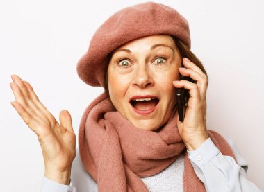 Pembe fularlı, bereli ve telefonda konuşan neşeli, başarılı yaşlı kadın. Olumlu duygular. Yaşam tarzı konsepti. Beyaz arkaplanı kapat.