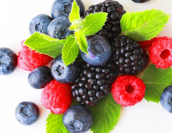 Yaprakla böğürtlen karıştır. Beyaz arka planda izole edilmiş çeşitli taze meyveler. Ahududu, yabanmersini, kızılcık, böğürtlen ve nane yaprakları. Kapat..