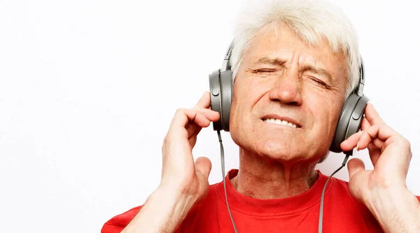 生活方式 茶道学和老年人的概念 白发老人戴着红色T恤 闭着眼睛 头戴耳机 头戴白色背带 听着音乐 — 图库照片