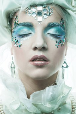 Parti, noel ve halk konsepti: Yeni yıl kostümlü parlak yaratıcı makyajlı güzel genç kadın gözleri kapalı, yakın plan portresi ile poz veriyor..