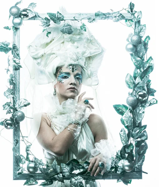 Parti, Noel ve insanlar: Noel karnavalı için kostüm giymiş güzel bir kadın Noel süslemeleri ve gümüş yapraklar çerçevesinde poz veriyor. Yaratıcı makyaj, saç stili.