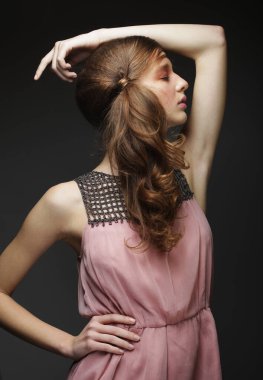 Pembe tonlarda güzel bir kadın. Siyah arka planda örgülü örgü ören genç bir kadın model. Saç stili trendde. Güzellik, moda, kozmetik ve kozmetik.