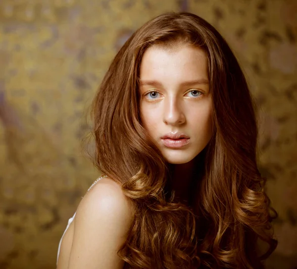 Moda, güzellik ve insan konsepti: Kameraya bakan uzun dalgalı saçlı çekici genç kadın