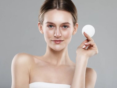 Makyaj malzemelerini çıkarmak için pamuk pedleri tutan güzel bir kadın. Temizlik, günlük rutin işler. Gri arkaplanda bir portre.