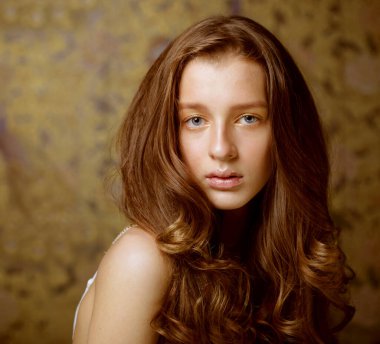 Uzun dalgalı saçlarıyla kameraya bakan çekici bir genç kadın.