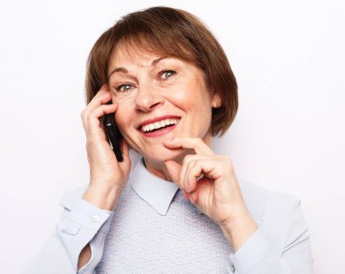 Modern yaşam tarzı, yaşlılar, iletişim ve elektronik aletler. Beyaz taşralı yerine akıllı telefonlu çekici yaşlı kadın.