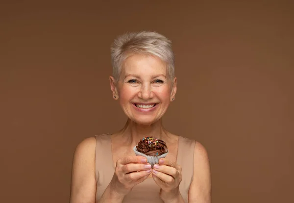 Mulher Idosa Com Cabelo Curto Segura Cupcake Chocolate Suas Mãos — Fotografia de Stock