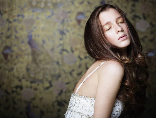 Moda, güzellik ve insan konsepti: Kameraya bakan uzun dalgalı saçlı çekici genç kadın