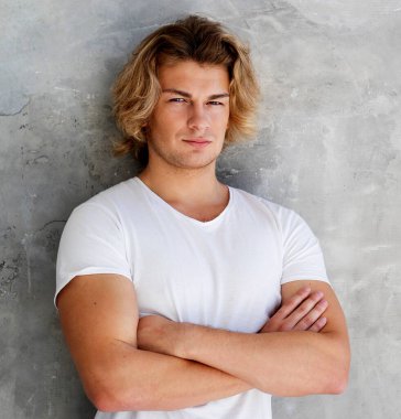 Zarif genç yakışıklı adam gri duvarın üzerinde poz veriyor. Stüdyo moda portresi.