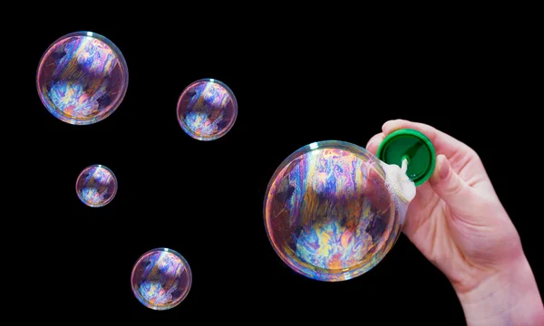 Soap bubbles and hand on black — Stock Photo, Image