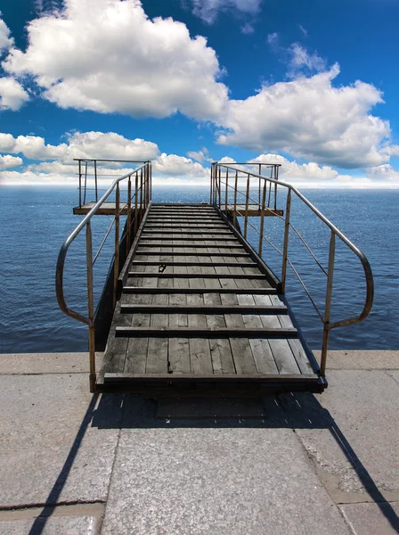 Pier in zee onder de blauwe hemel en wolken — Stockfoto