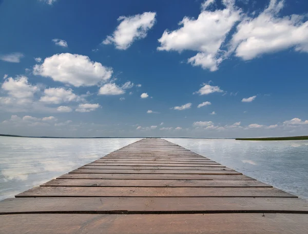 Ahşap iskele mavi gökyüzünün altında büyük göl — Stok fotoğraf