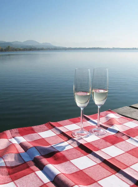 Two champagne glasses against a lake — Stok fotoğraf