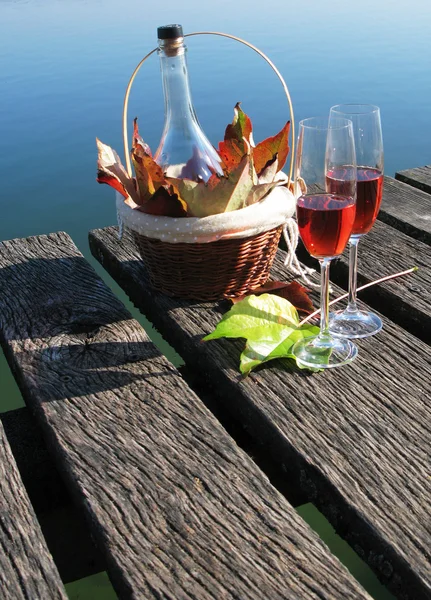 Deux verres à vin et des feuilles d'automne sur une jetée en bois — Photo