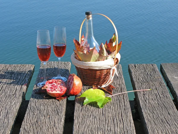 Coppia di occhiali da vino, melograno e foglie autunnali contro un lak — Foto Stock