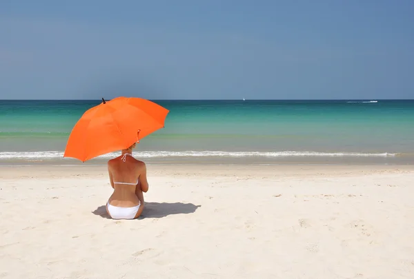 Meisje met een oranje paraplu op het zandstrand — Stockfoto