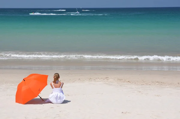 Chica con un paraguas naranja en la playa de arena —  Fotos de Stock