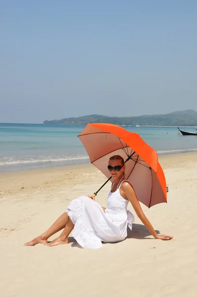 Mädchen mit orangefarbenem Regenschirm am Sandstrand — Stockfoto