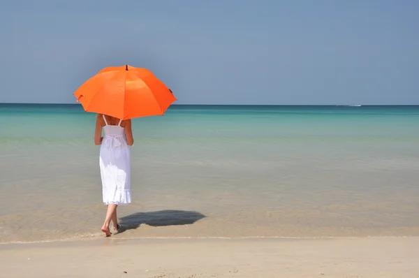 Flicka med ett orange paraply på sandstranden — Stockfoto