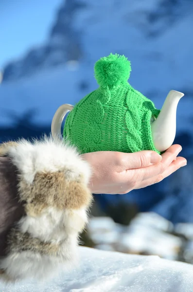 Tea pot in the knotted cap in the hand againstmountain scenery — Stock Photo, Image