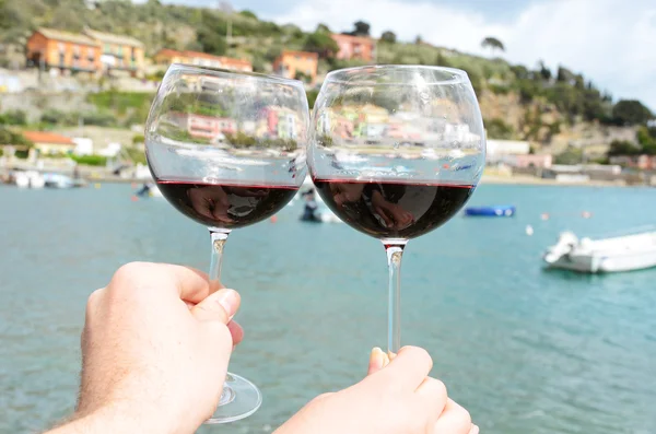 Deux verres à vin dans les mains contre le port de Portvenere , — Photo