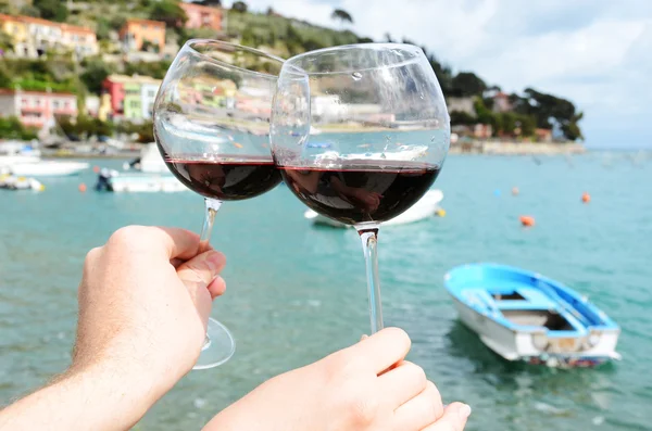 Deux verres à vin dans les mains contre le port de Portvenere , — Photo
