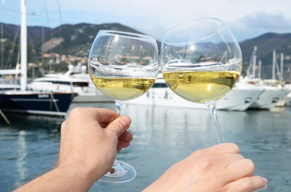 Pair of wineglasses in the hands against the yacht pier of La Sp — Stock Photo, Image