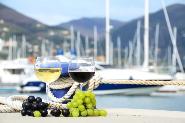 Pair of wineglasses and grapes against the yacht pier of La Spez — Stock Photo, Image