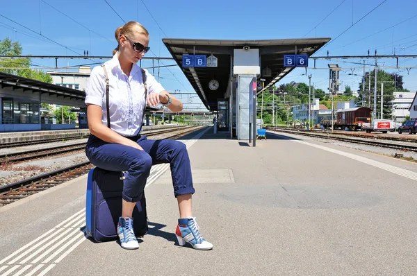 Flicka vid järnvägsstationen titta på hennes klocka — Stockfoto