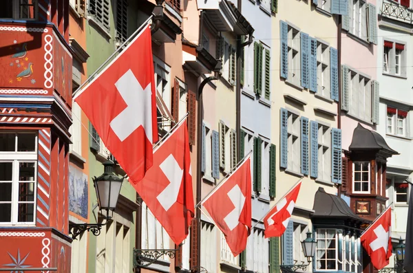 A svájci nemzeti zászlókkal díszített Zürichben régi utca — Stock Fotó