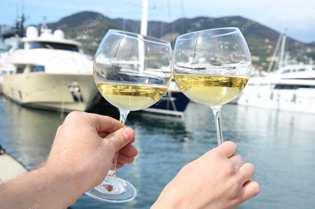 Pair of wineglasses in the hands against the yacht pier of La Sp