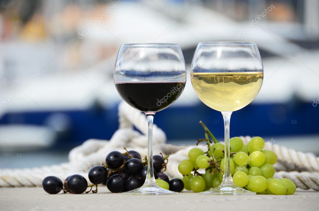 Pair of wineglasses and grapes against the yacht pier of La Spez