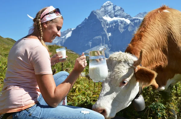 Girl with a jug of milk and a cow. Jungfrau region, Switzerland — Stock Photo, Image