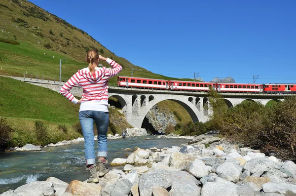 Girl looking at the train, which crosses a bridge. Switzerland — Stock Photo, Image