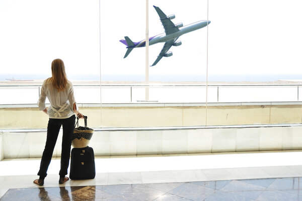 Girl at the airport window looking to the ocean