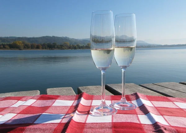 Two champagne glasses against a lake — Stok fotoğraf