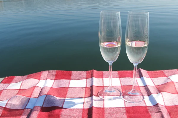 Two champagne glasses against a lake — Stok fotoğraf