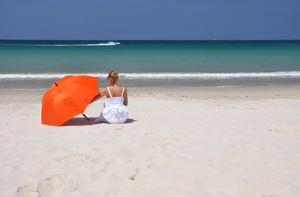 Дівчина з помаранчевою парасолькою на піщаному пляжі — стокове фото