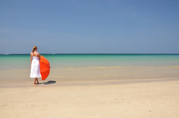 Ragazza con un ombrellone arancione sulla spiaggia di sabbia — Foto Stock