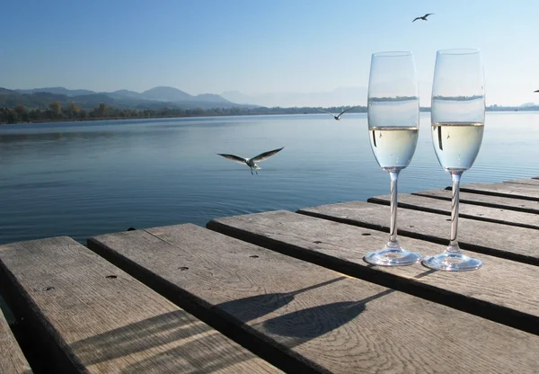 Two champagne glasses against a lake — Stok fotoğraf