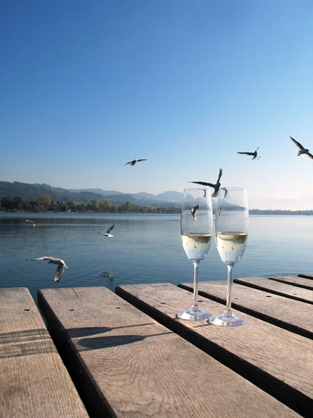 Two champagne glasses against a lake — Stok fotoğraf