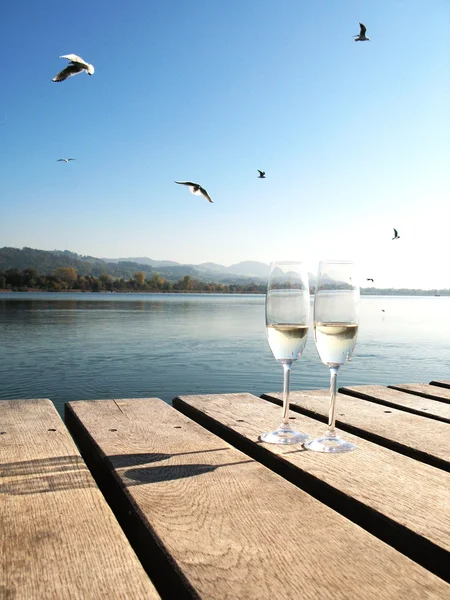 Two champaign glasses against a lake — Stok fotoğraf