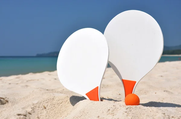 Zwei Schläger und ein Ball am Sandstrand — Stockfoto