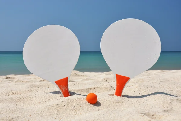 Two racket and a ball on the sandy beach — Stock Photo, Image