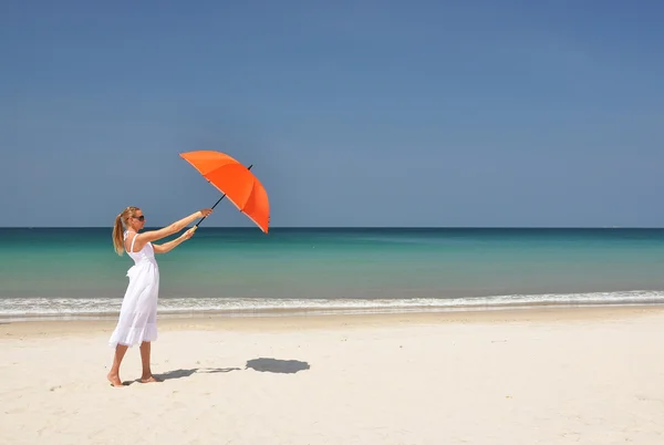 Meisje met een oranje paraplu op het zandstrand — Stockfoto