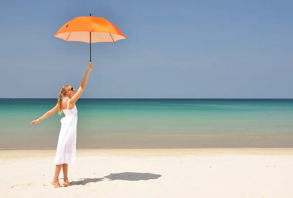 Mädchen mit orangefarbenem Regenschirm am tropischen Strand — Stockfoto