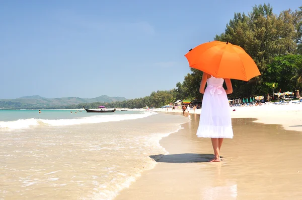 Flicka med ett orange paraply på sandstranden — Stockfoto